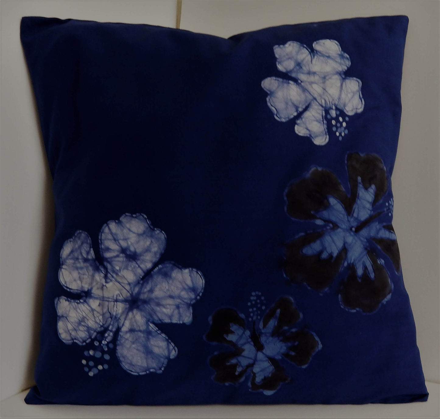 Navy blue pillow featuring batik hibiscus flowers.
